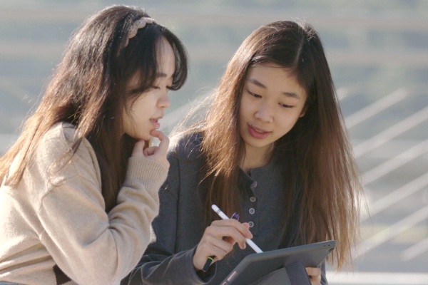 Two students browsing scholarship information on their tablets